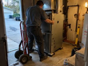 Setting a new furnace in place during installation by Aegis Heating and Air