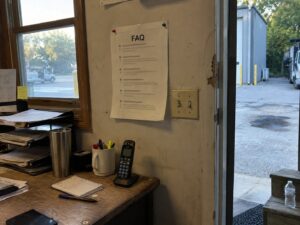 Printed FAQ sheet pinned on a shop office wall by Aegis Heating and Air
