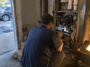 Inspecting the interior of an open furnace cabinet by Aegis Heating and Air