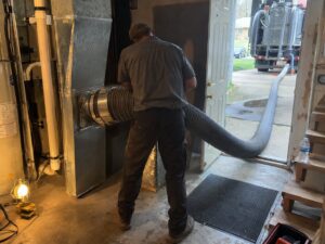 Truck-mount HEPA duct cleaning attached to a plenum by Aegis Heating and Air